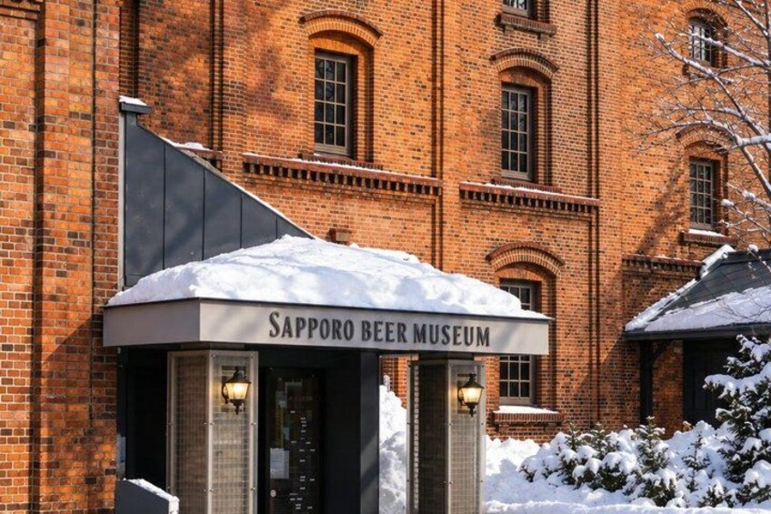 A brick building with a sign reading 'Sapporo Beer Museum' and snow on the roof and ground. 5
