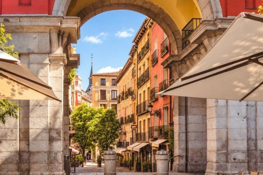 A street with buildings, an archway, and a tree. 3