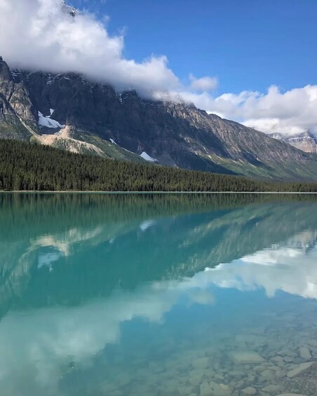 Un lago de montaña cristalino con reflejos, rodeado de laderas boscosas y picos nevados. 2