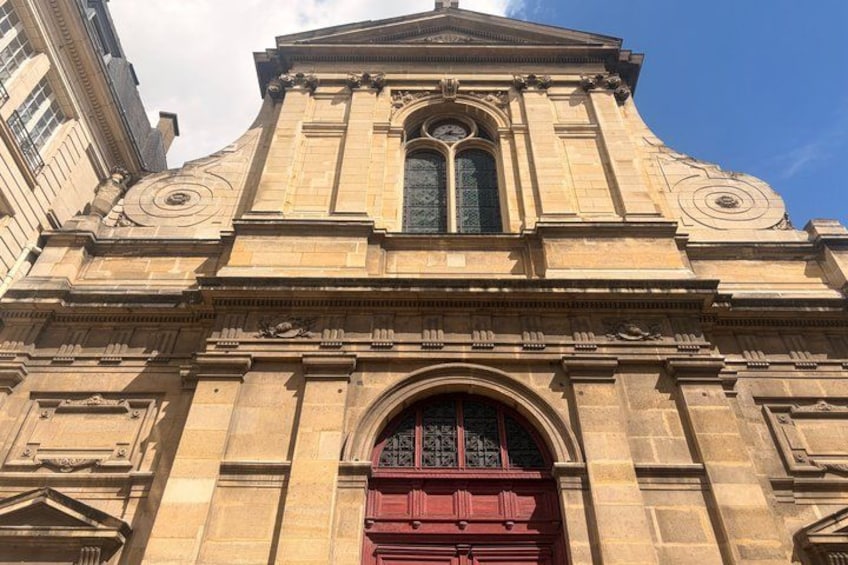 A large stone building with a central arched window and a red door. 4