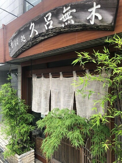 Un restaurante con un letrero de madera y plantas de bambú. 5