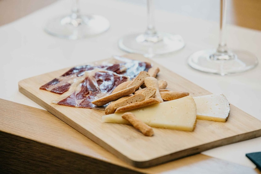 Ein Holzboden mit verschiedenen Fleischsorten, Käse, Crackern und zwei Weingläsern. 2