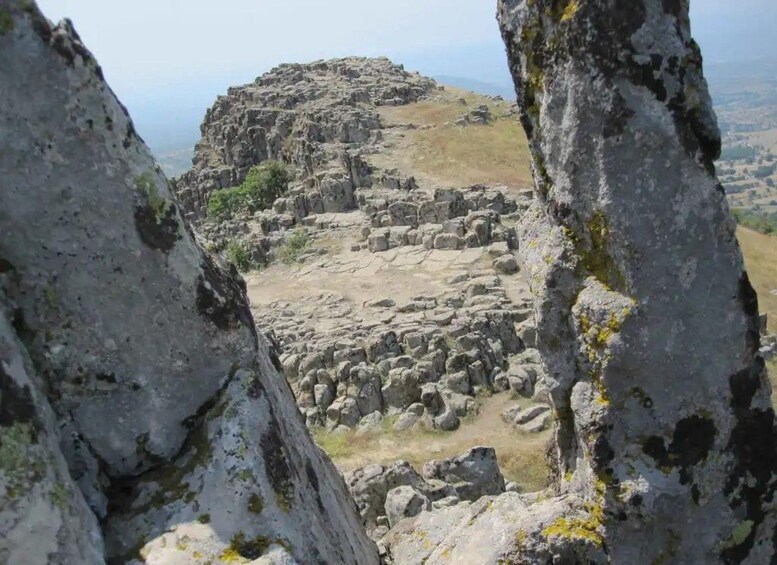 Un paisaje rocoso con grandes rocas y una colina al fondo. 3