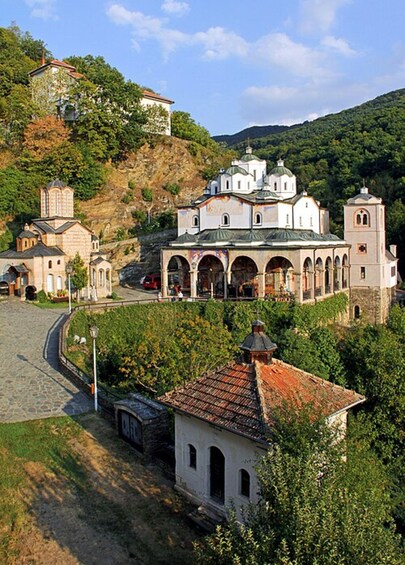Una iglesia histórica con múltiples cúpulas y torres de campanario, rodeada de exuberante vegetación y un paisaje montañoso. 4