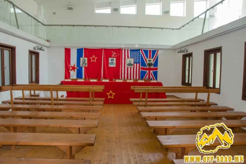 Un salón con bancas de madera, un atril y banderas de China, EE. UU. y Reino Unido. 5