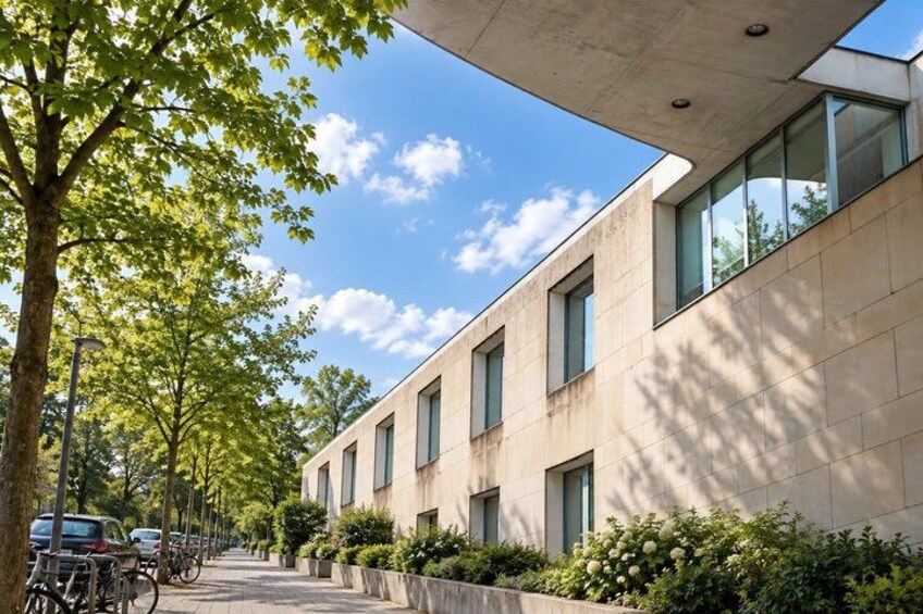 A modern building with large windows, a tree-lined street, and parked bicycles. 4