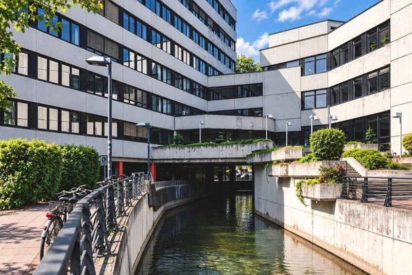 A modern building with a canal running through it, surrounded by greenery and bicycles. 3