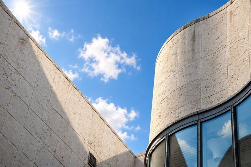 A curved concrete building with a clear sky and clouds. 5