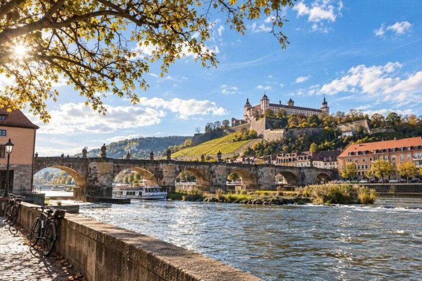 A river with a stone bridge, a castle on a hill, and a boat. 3