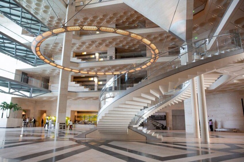A modern interior with a central spiral staircase, glass railings, and a circular light fixture. 3