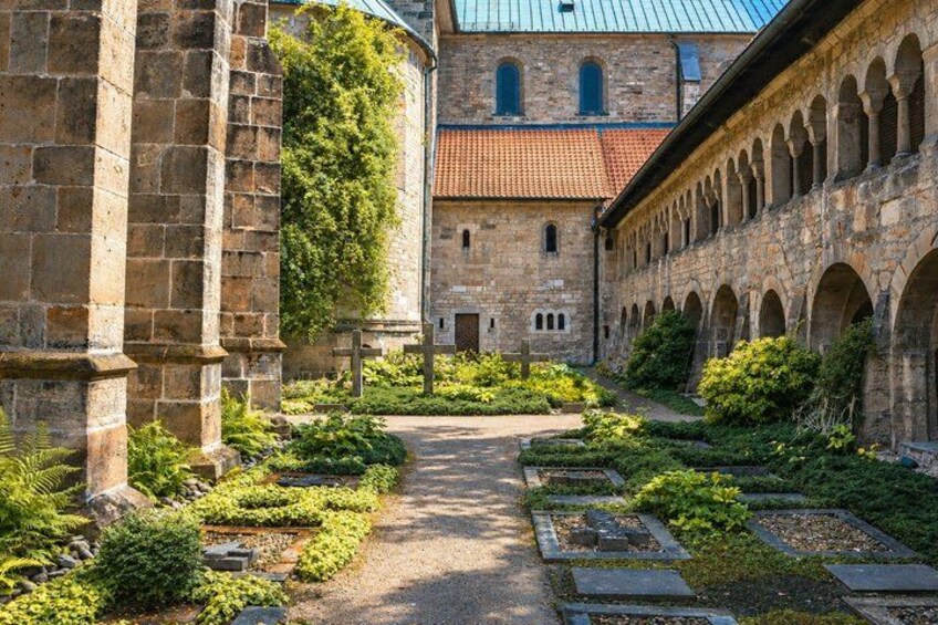 A stone building with a pathway, greenery, and a red-tiled roof. 2