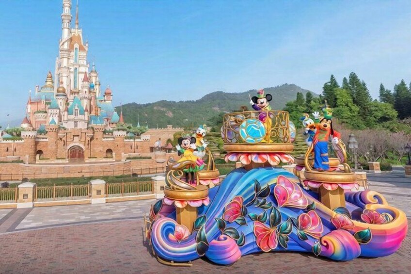 A colorful carousel with Disney characters in front of a castle. 5