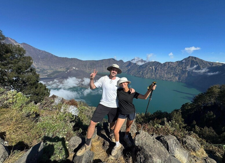 Zwei Personen posieren auf einem Felsen mit einem See und Bergen im Hintergrund. 3