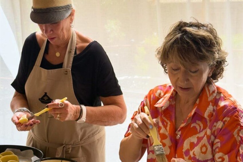 Two people cooking, one wearing an apron and the other in a patterned shirt. 2