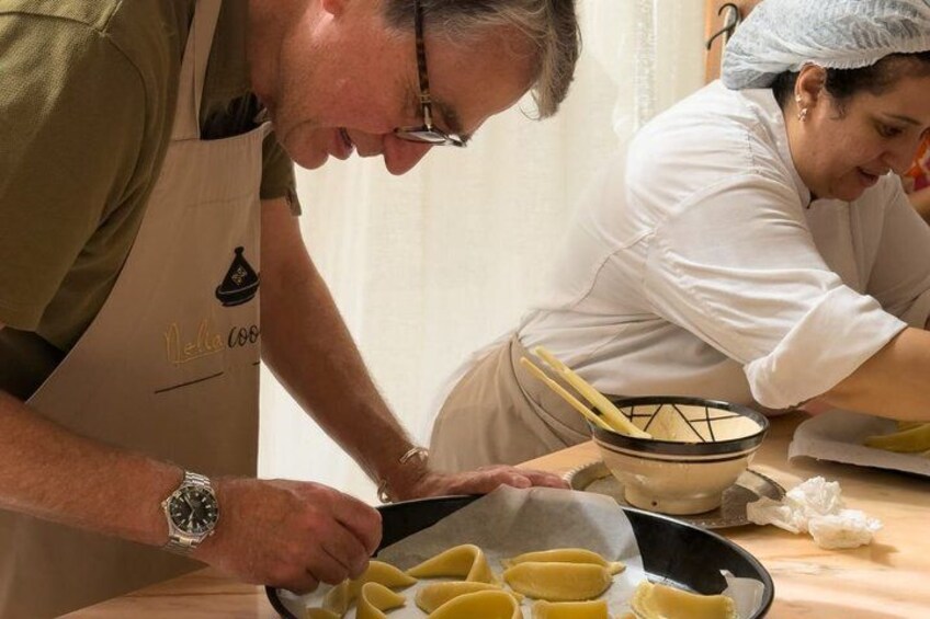 A person in a kitchen preparing food, with a focus on pasta. 3