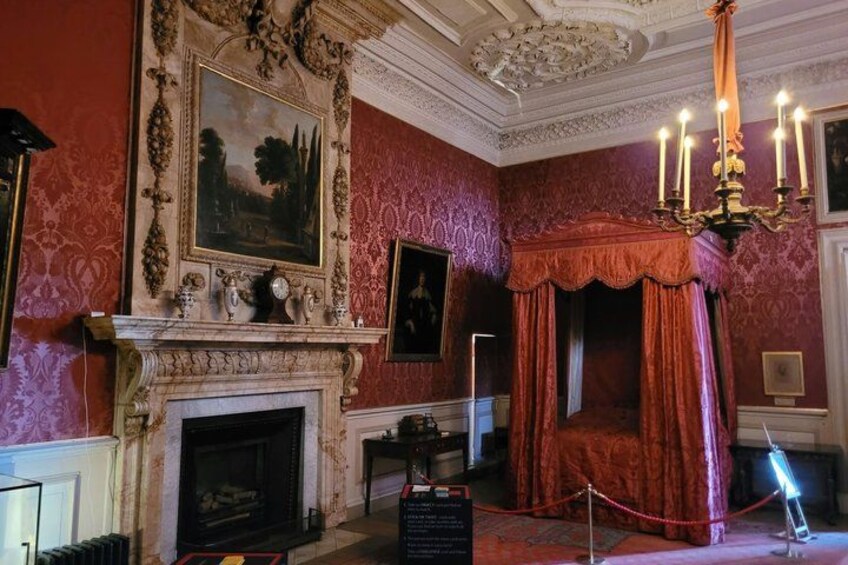 A room with a fireplace, a painting, a chandelier, and a red curtain. 3