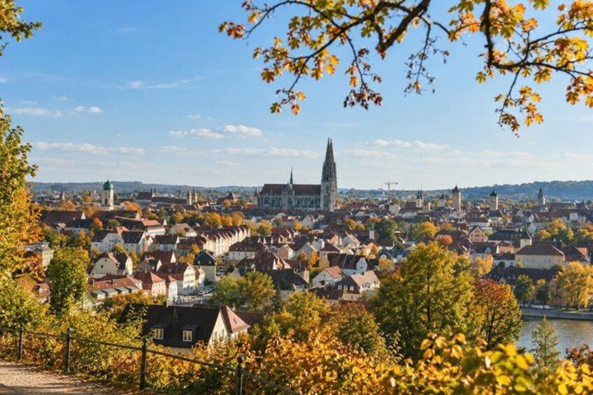 A town with historic buildings, a prominent church spire, and autumn foliage. 4