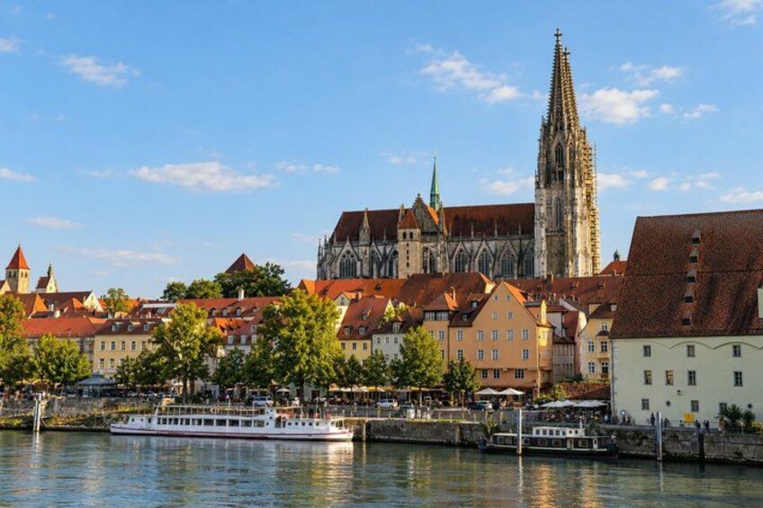A river with a boat, historic buildings, and a tall church spire. 2