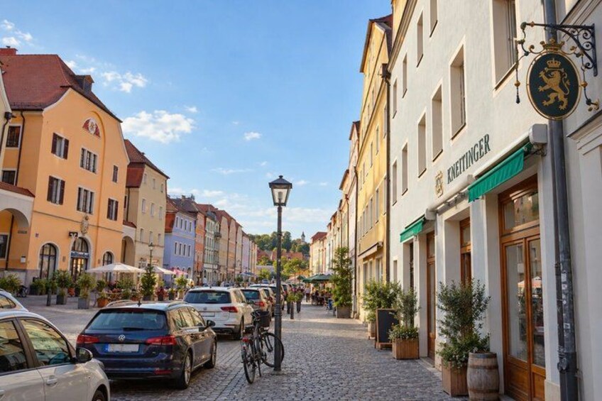A cobblestone street lined with historic buildings, a bicycle, and parked cars. 3