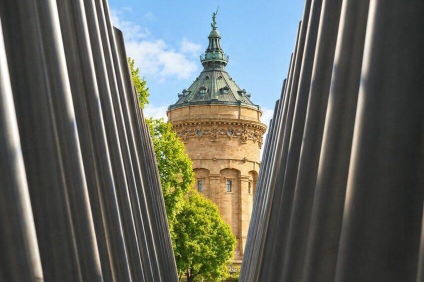 A round building with a green dome and a clock, framed by metal structures. 3