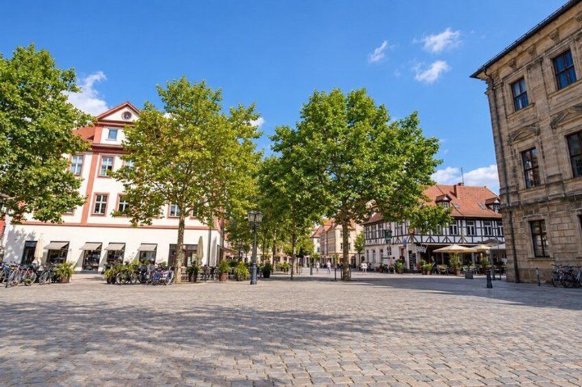 A cobblestone square with trees, historic buildings, and bicycles. 2