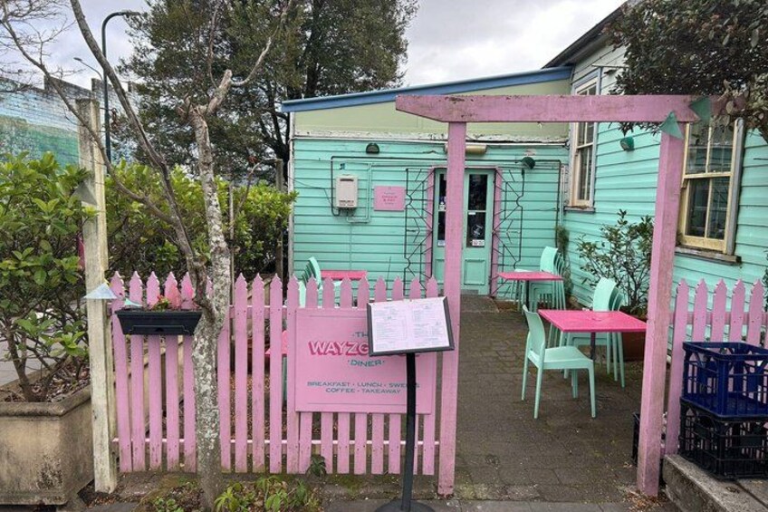 A pink and turquoise outdoor café with tables and chairs. 2