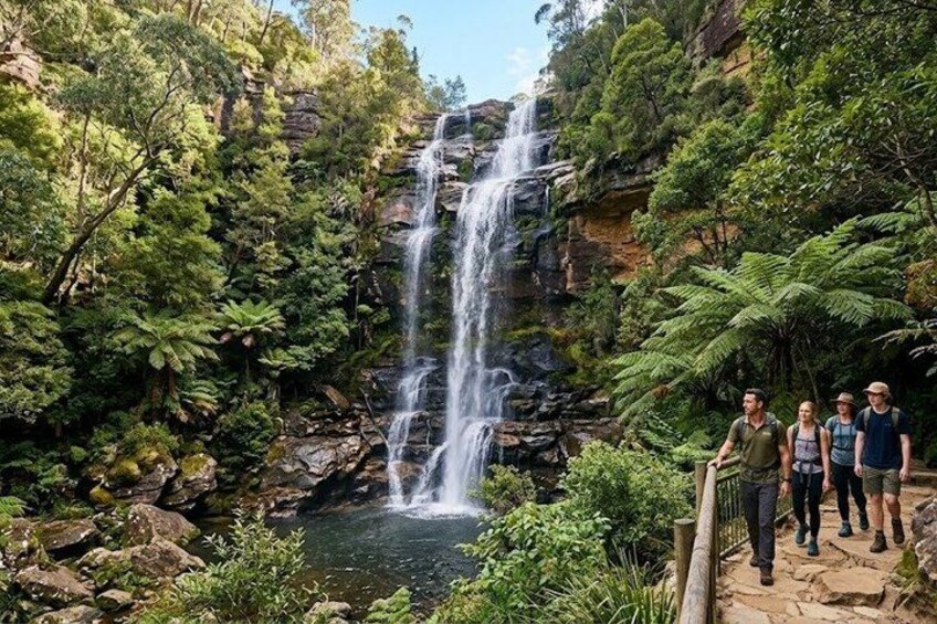 A waterfall surrounded by lush greenery and a group of people standing on a path. 3