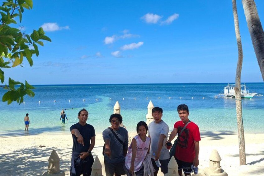 A beach with people, clear water, and a boat in the distance. 3