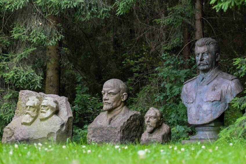 A statue of a man in uniform, surrounded by trees and grass. 2