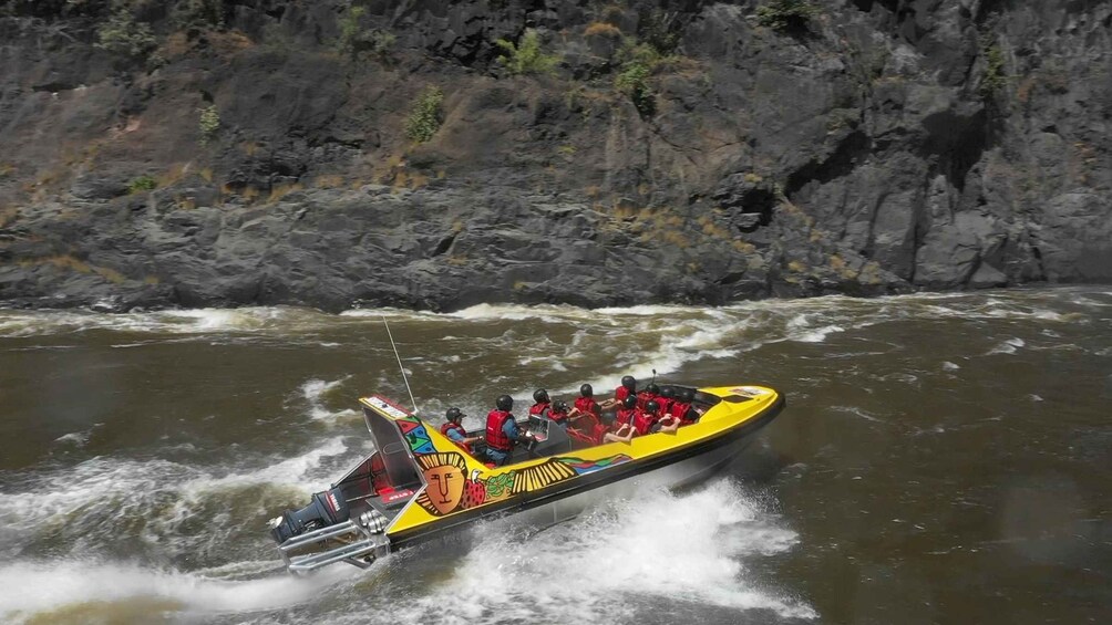 A yellow boat with passengers wearing life jackets, navigating a river with rocky banks. 2