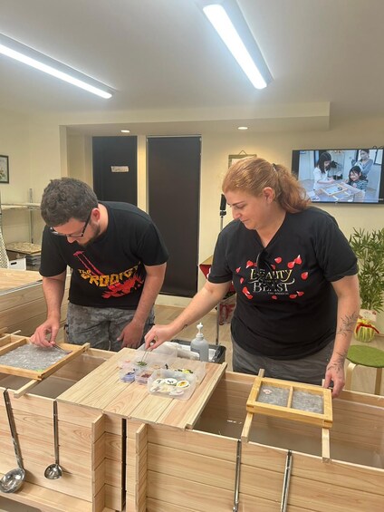 Dos personas trabajando con marcos y recipientes de madera, posiblemente en un taller o espacio de manualidades. 3