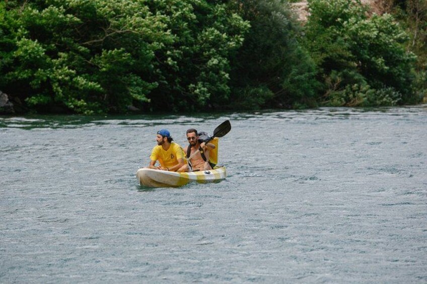 Two people kayaking on a river surrounded by dense greenery. 2