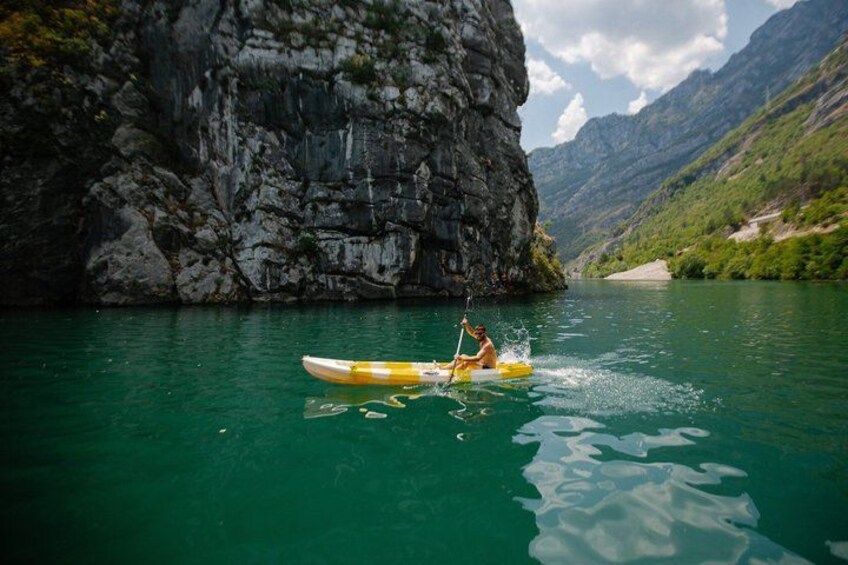 A kayak on a calm river with rocky cliffs in the background. 5