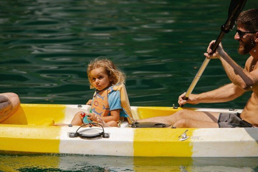 A person in a yellow and white boat with a child, using paddles. 3