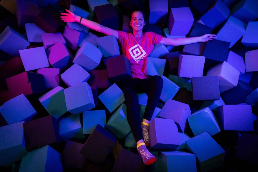 A person sitting amidst colorful foam blocks with arms outstretched. 4