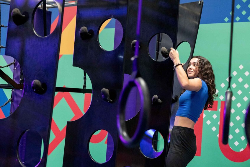 A person interacting with a colorful, abstract wall installation with circular cutouts. 5