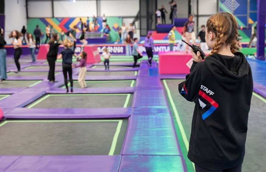 A trampoline park with multiple trampolines and people jumping. 2