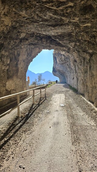 Un túnel rocoso con barandilla metálica, que ofrece una vista despejada de montañas. 2