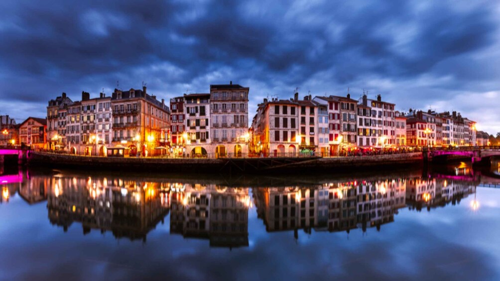 Un paisaje urbano frente al agua al anochecer, con edificios iluminados que se reflejan en el agua. 5
