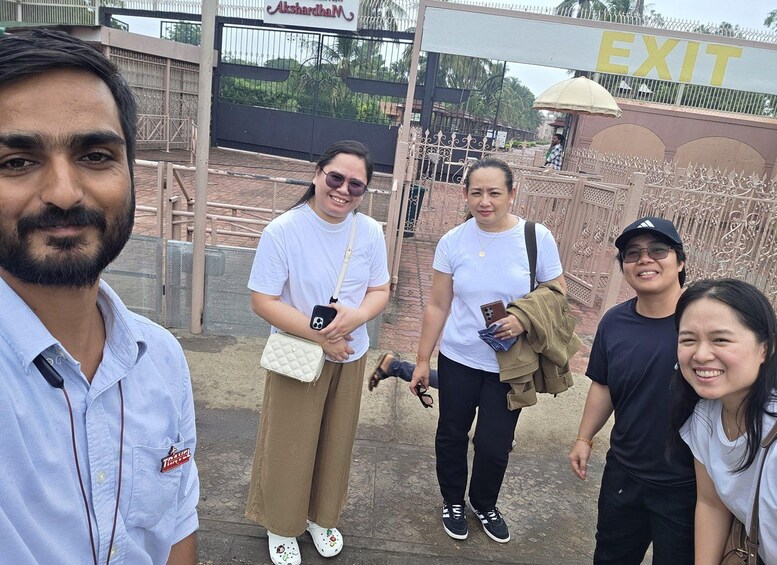 A group of people standing in front of a gate with an 'EXIT' sign. 2