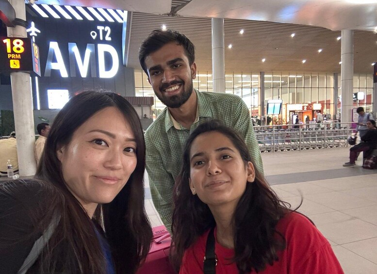 A group of people in an airport terminal with a sign for gate T2 and a pillar with an 18 PRM sign. 1