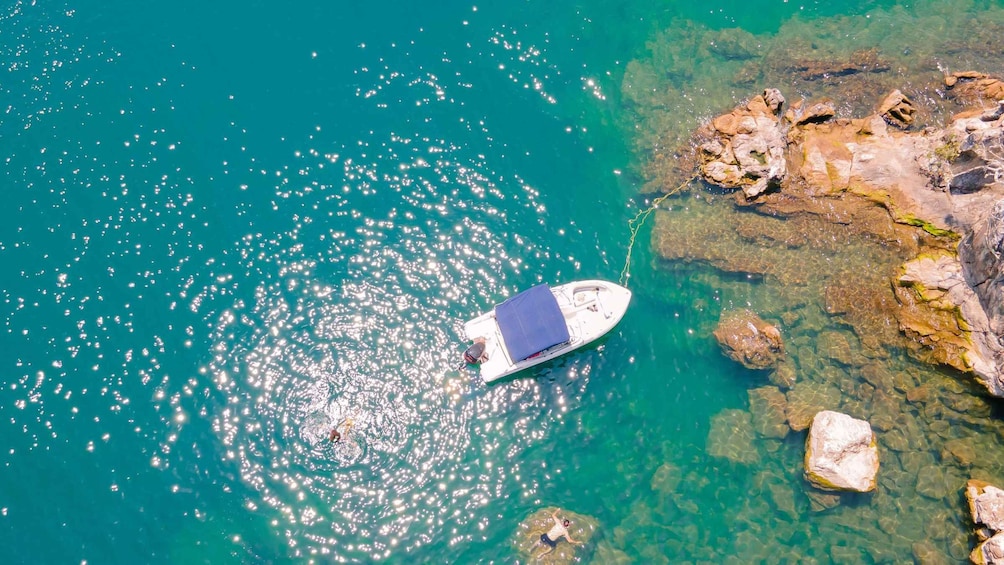 Un barco anclado cerca de una costa rocosa con agua turquesa transparente. 1