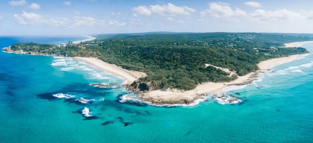 Paisaje costero con playa, zona boscosa y aguas azul turquesa. 2