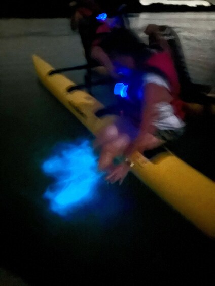 A person in a yellow kayak with blue lights, wearing a life jacket, on a body of water. 2