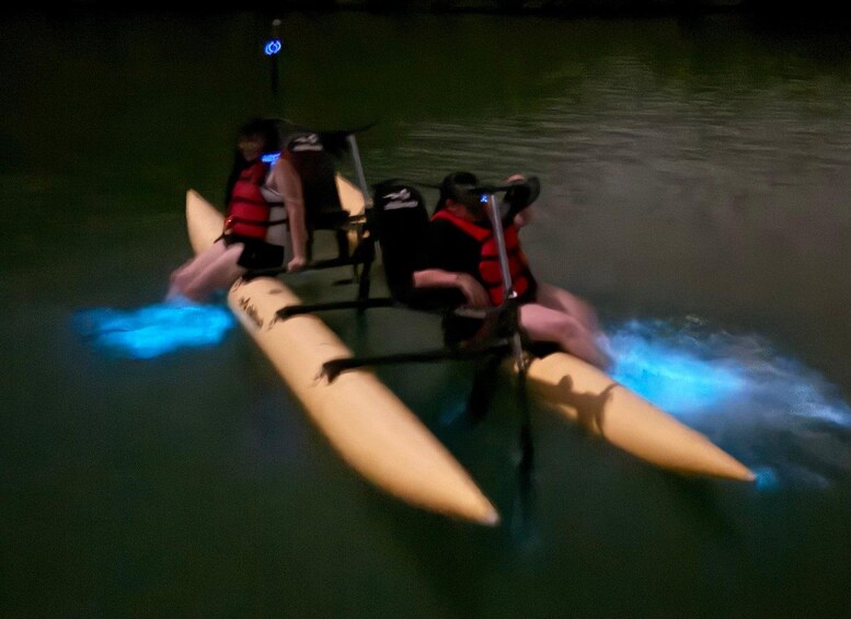 Two people on a kayak with blue lights on the sides. 1