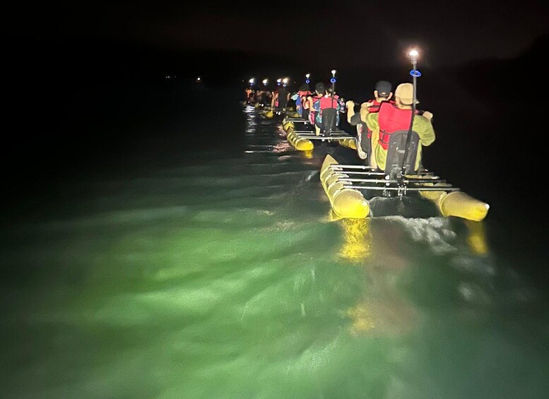 People walking on a floating platform in a body of water at night. 3
