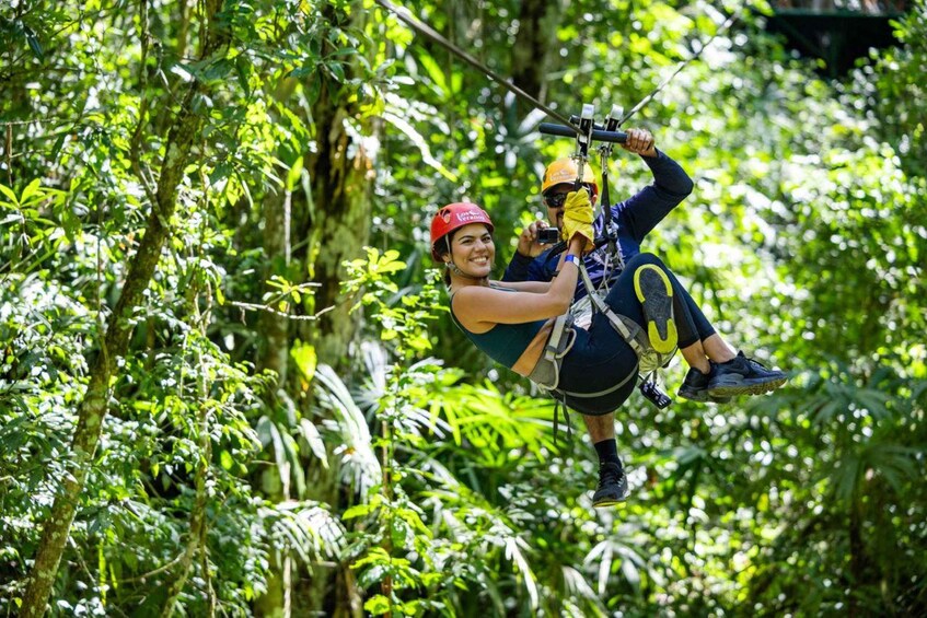 Una persona haciendo tirolesa a través de un bosque frondoso. 1