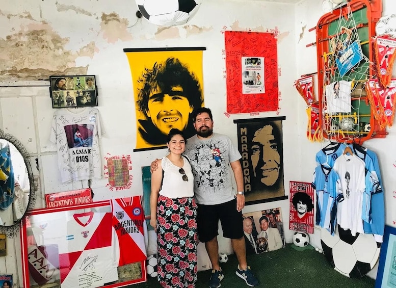 Une pièce où sont exposés divers objets de collection liés au sport, notamment un ballon de football, des maillots et des affiches. 1