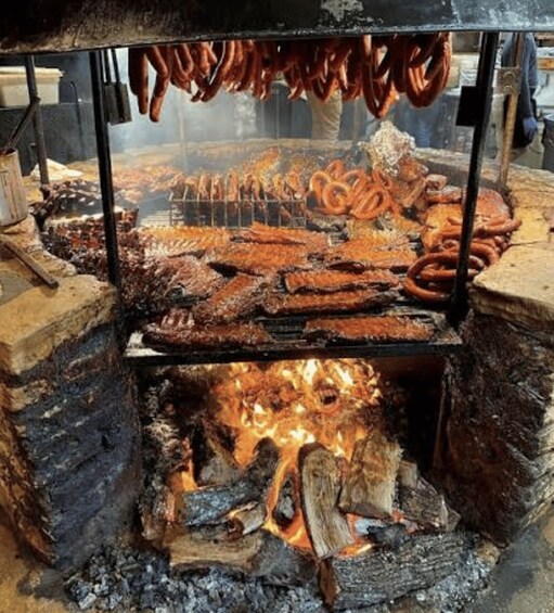 Un montaje tradicional de cocina al aire libre con diferentes carnes asándose sobre un fuego abierto. 1