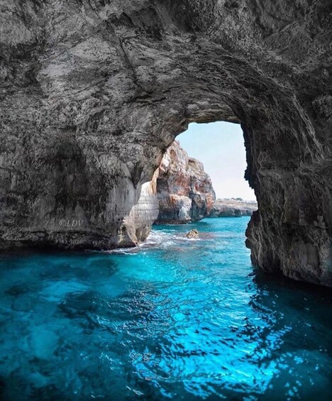 Une arche naturelle en roche surplombant une eau turquoise. 1